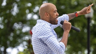 Mandela Barnes speaks into a hand-held microphone while pointing with his other hand.