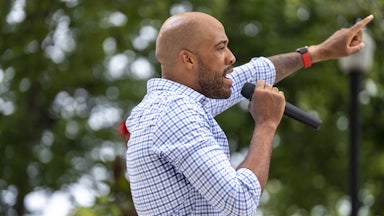 Mandela Barnes speaks into a hand-held microphone while pointing with his other hand.