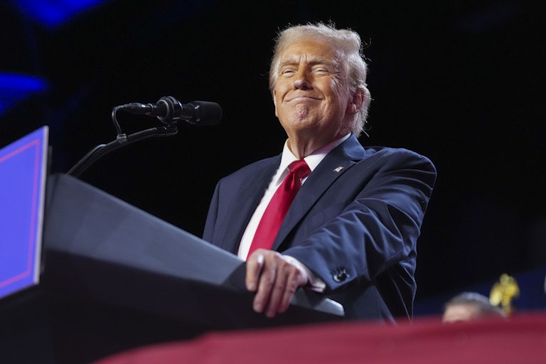 Donald Trump smiles while standing at a podium