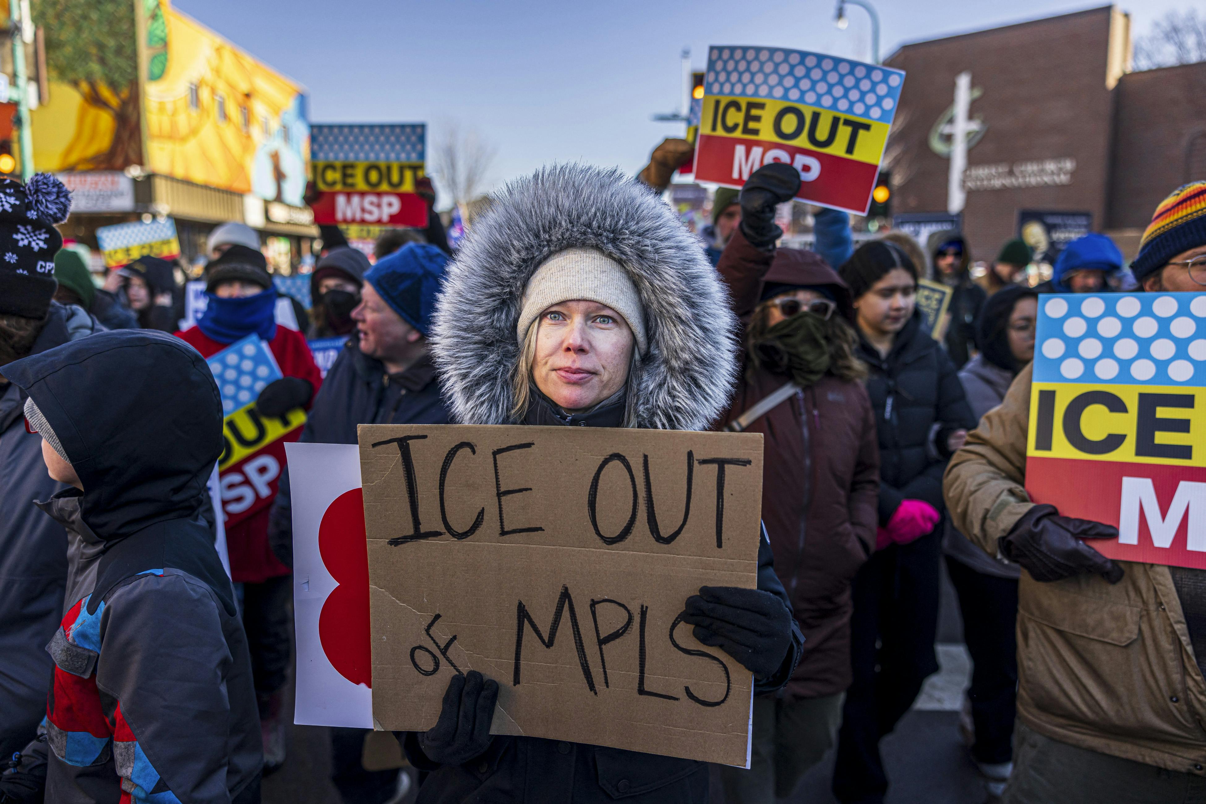 A woman holds a sign reading ICE OUT OF MPLS
