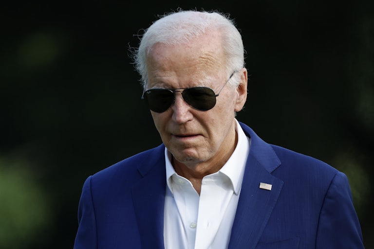 Joe Biden wears sunglasses outside and looks downward