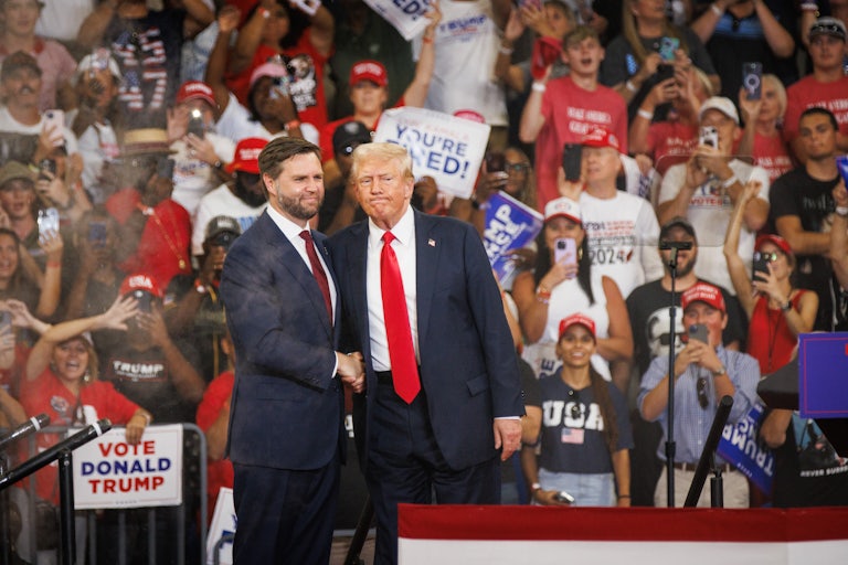 J.D. Vance and Donald Trump shake hands on stage at a rally