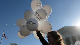 A protester holds balloons calling for religious freedom outside the Supreme Court.