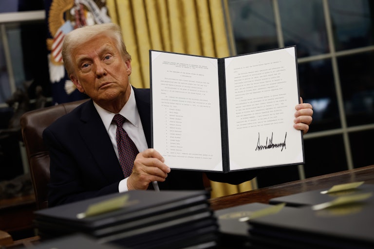 Donald Trump holds up a signed executive order in the Oval Office