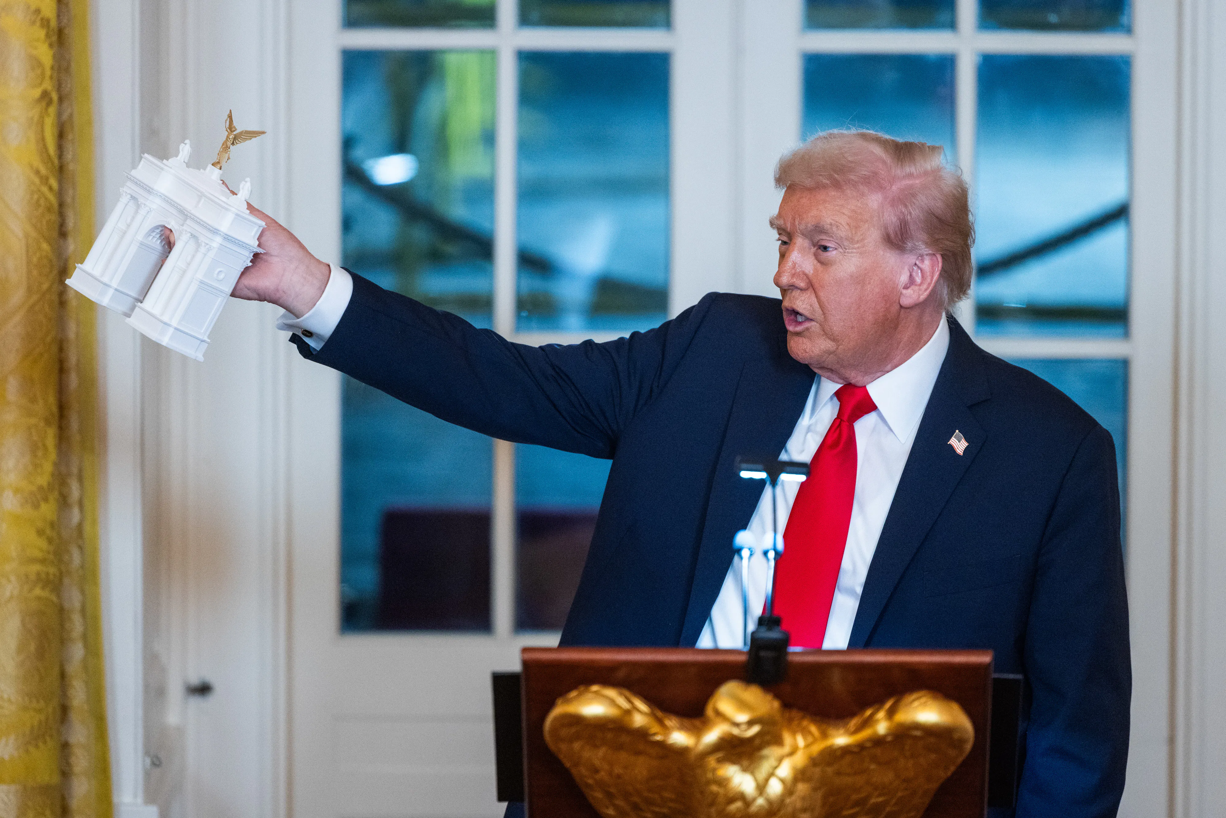 Donald Trump holds a model of the planned Triumph Arch during a dinner in the East Room of the White House.
