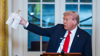Donald Trump holds a model of the planned Triumph Arch during a dinner in the East Room of the White House.