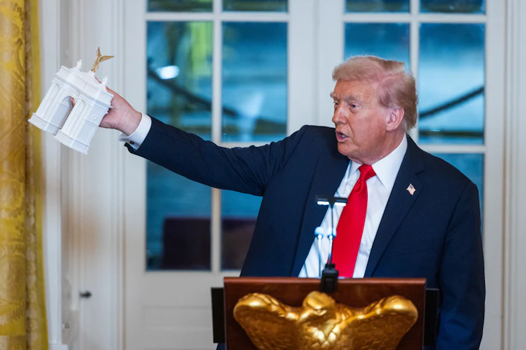 Donald Trump holds a model of the planned Triumph Arch during a dinner in the East Room of the White House.