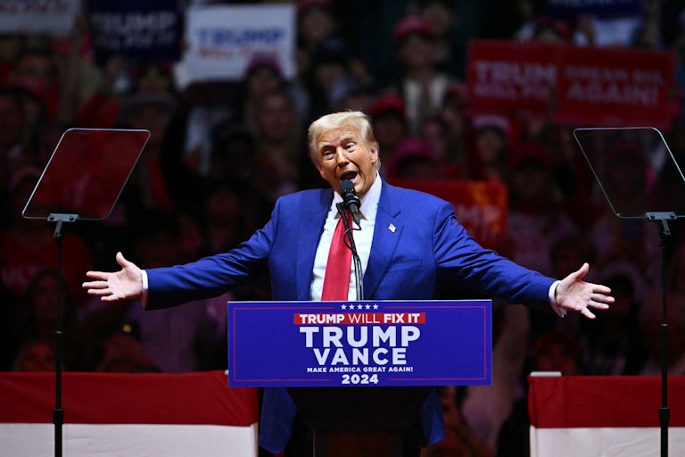 Donald Trump holds his arms out while speaking at a campaign rally