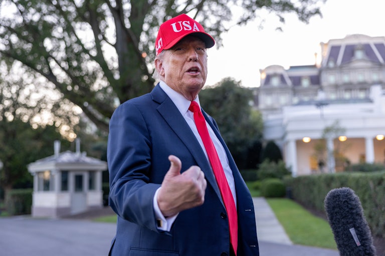 Donald Trump wears a red USA cap while he speaks to reporters outside the White House.
