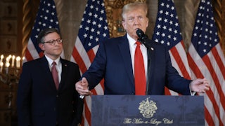 Donald Trump speak at a lectern while Mike Johnson stands behind him and looks on
