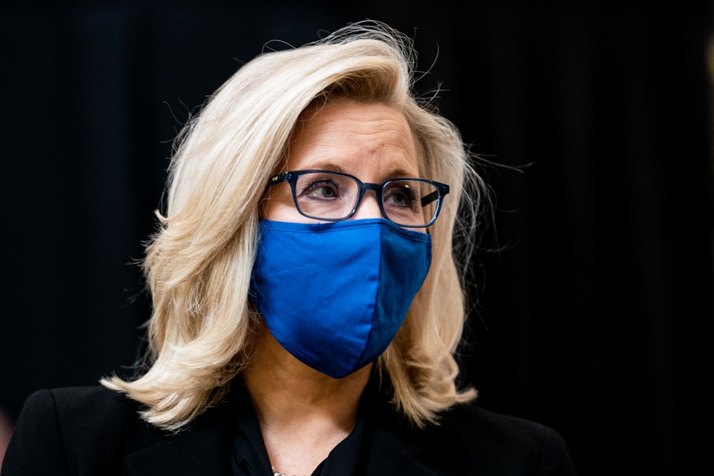 Liz Cheney wearing a blue mask, against a black background
