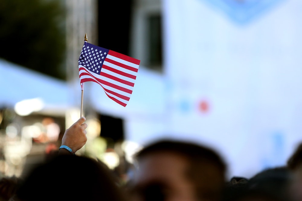 A person holds up an American flag in City Hall Plaza in Boston, Massachusetts.