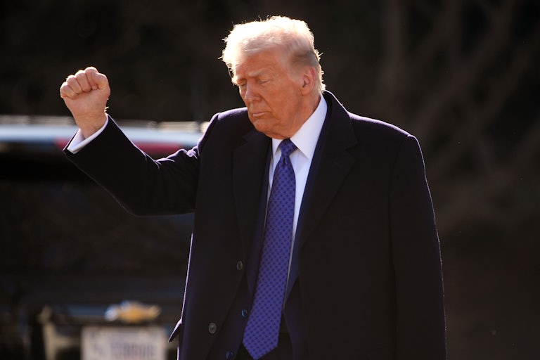 Donald Trump pumps his fist and looks down while walking outside the White House