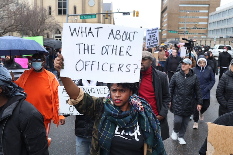 A Black protester holds a sign reading, "What about the other officers?"