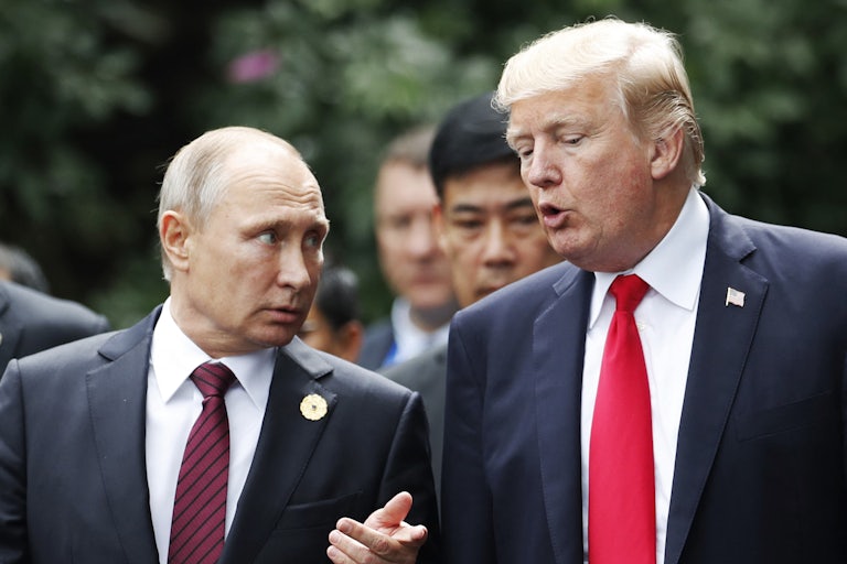 Putin stands on the left, explaining something to Trump on the right outdoors