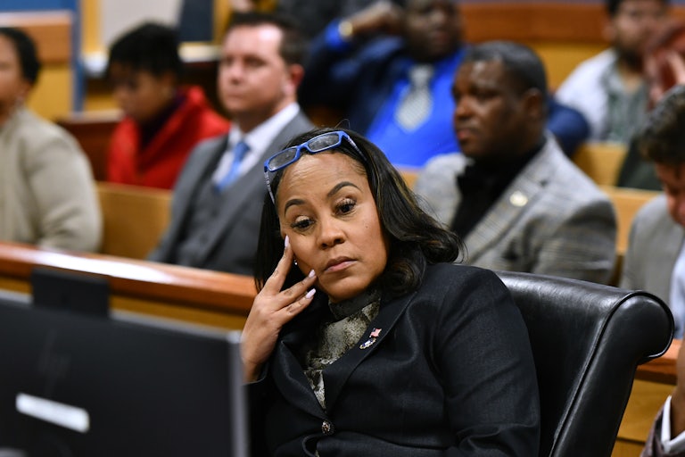 Fani Willis rests her face on her hand while sitting in a courtroom