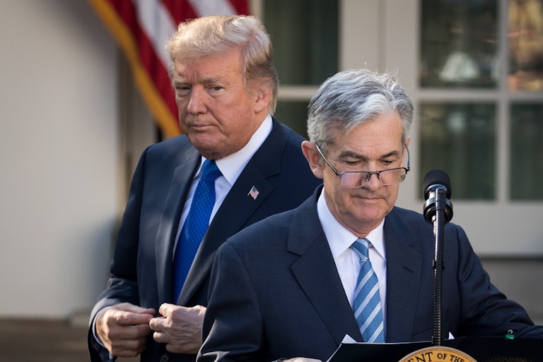 Donald Trump scowls as he stands behind Jay Powell