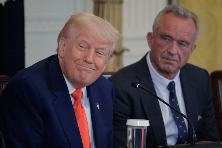 Donald Trump smiles as he sits next to Health and Human Services Secretary Robert F. Kennedy Jr..