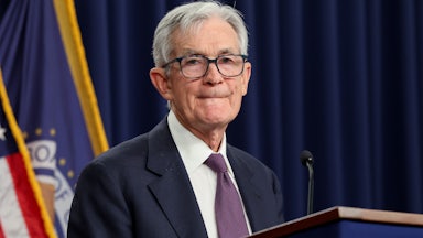 Federal Reserve Chair Jerome Powell purses his lips while standing behind a podium.