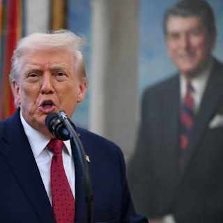 Donald Trump gestures and speaks at a microphone in the Oval Office