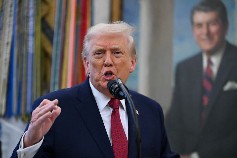 Donald Trump gestures and speaks at a microphone in the Oval Office