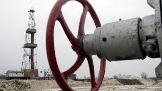 A wheel to shut off a valve appears in the foreground, with further infrastructure in the background.
