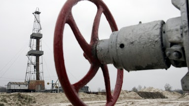 A wheel to shut off a valve appears in the foreground, with further infrastructure in the background.