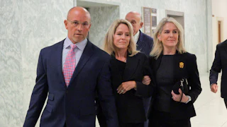 Lesley Groff holds the hand of a man and woman who is smiling.