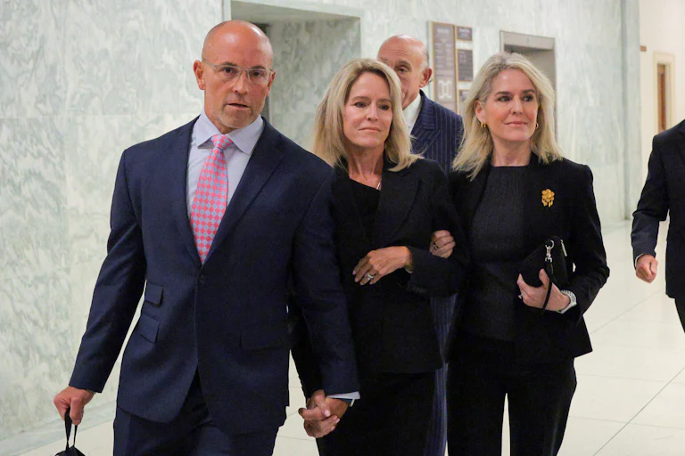 Lesley Groff holds the hand of a man and woman who is smiling.