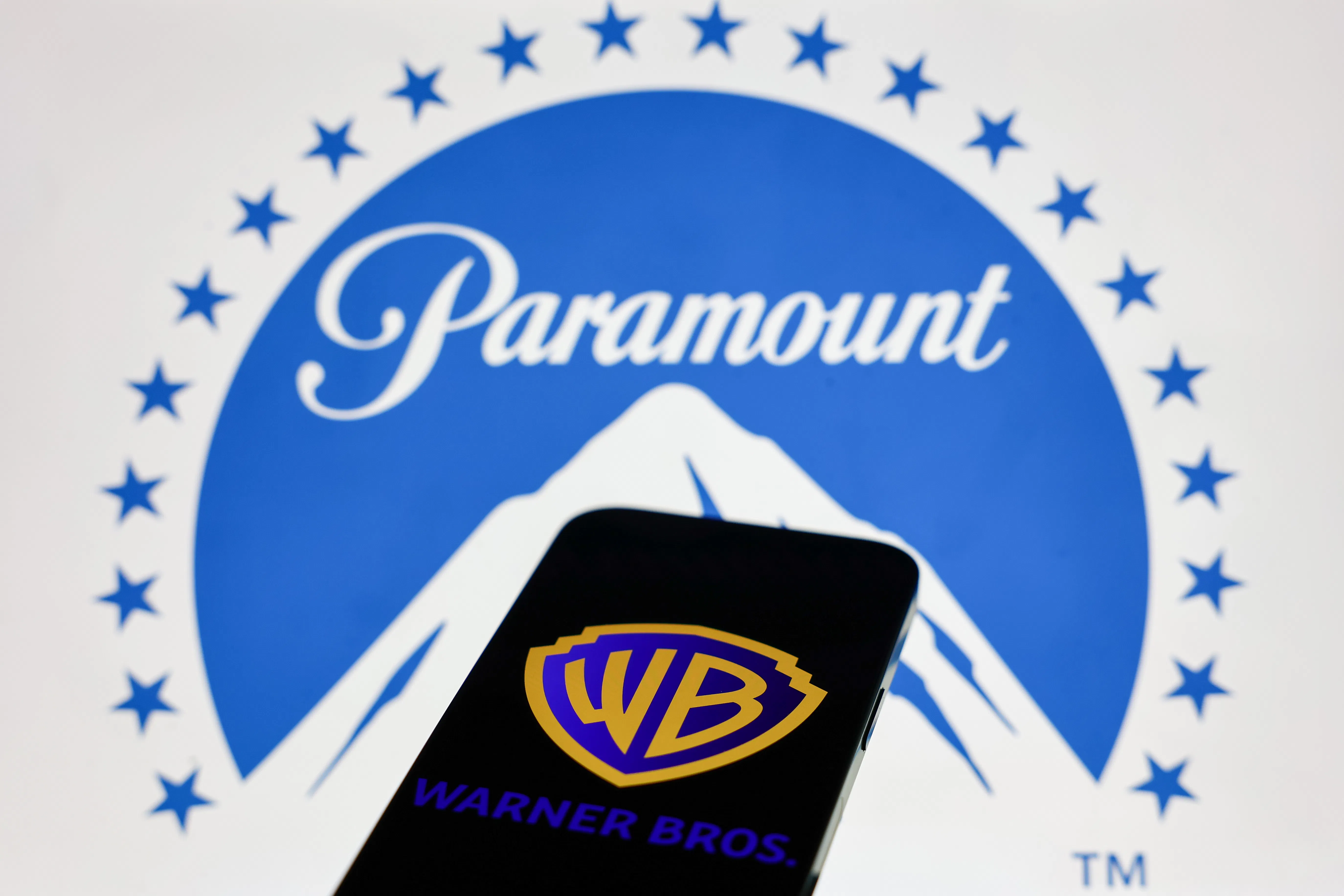 A phone with the Warner Bros. logo and a laptop screen with the Paramount logo