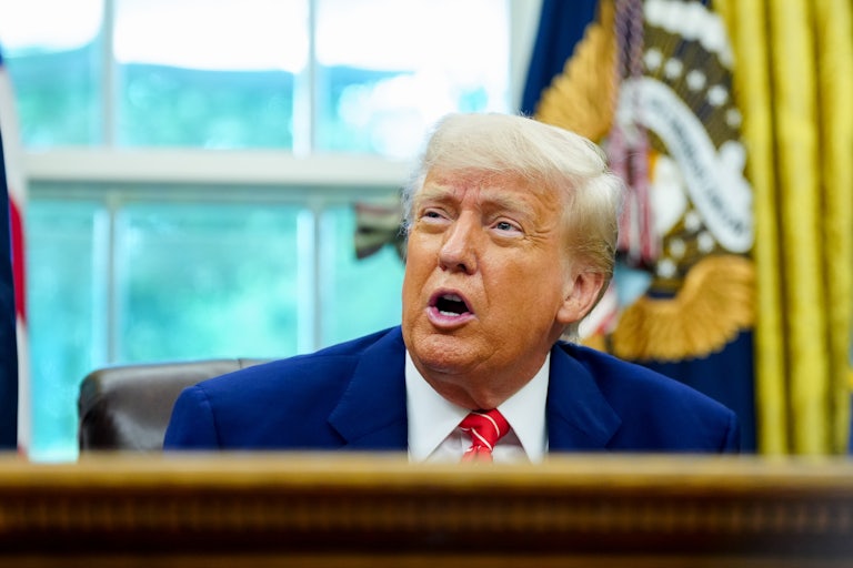 Donald Trump speaks while sitting at his desk in the Oval Office