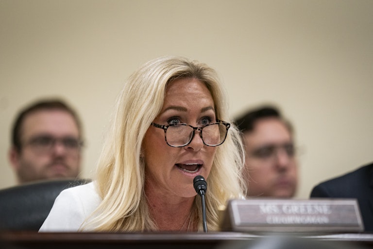 Marjorie Taylor Greene speaks during a congressional hearing and raises her eyebrows as if in surprise.
