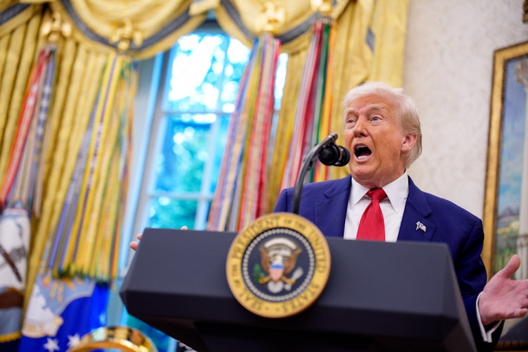Donald Trump gestures while speaking at a podium in the Oval Office