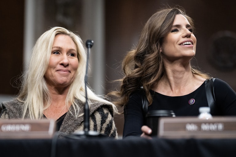 Marjorie Taylor Greene and Nancy Mace smile while sitting next to each other