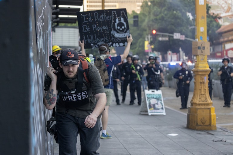 A member of the press ducks as police fire non-lethal munitions at protesters in Los Angeles.