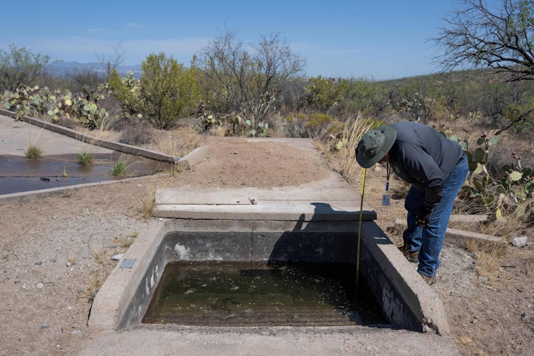 A man checks water levels in a wildlife water catchment