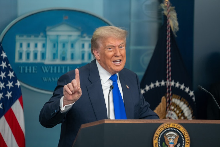 Donald Trump raises his finger while speaking at the podium in the White House press briefing room
