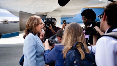 Kamala Harris talks to reporters on a tarmac.