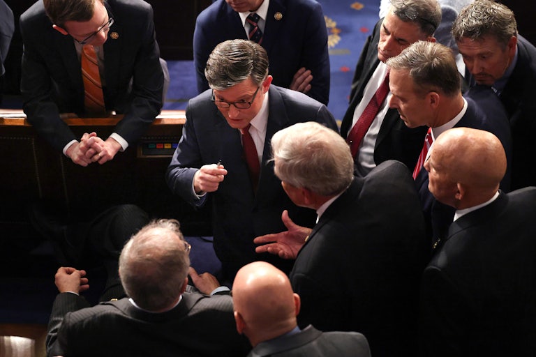 Mike Johnson gestures while speaking to other representatives
