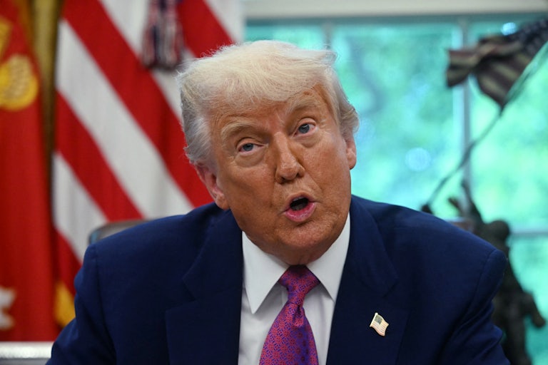 Donald Trump speaks to reporters while sitting in the Oval Office