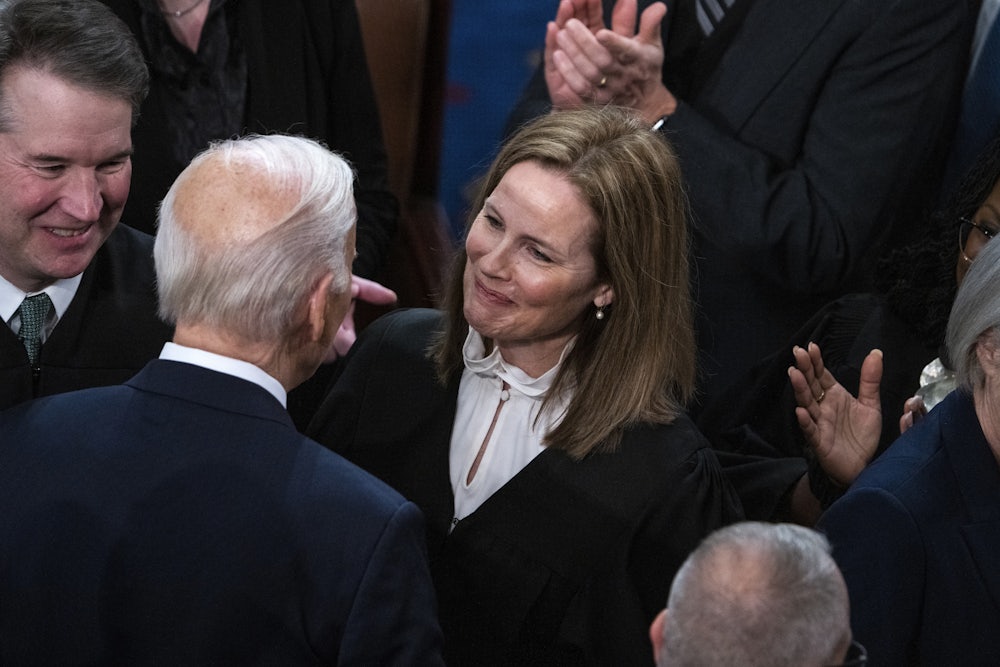 Biden greets Coney Barett, surrounded by people.