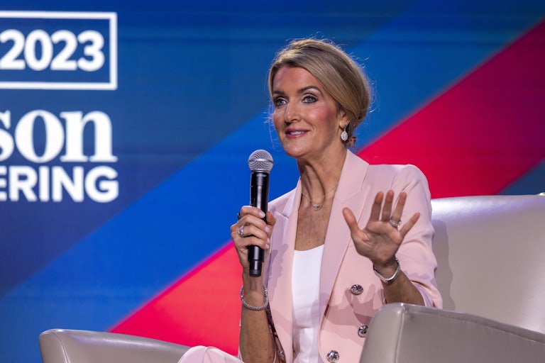 Kelly Loeffler holds up a microphone and gestures