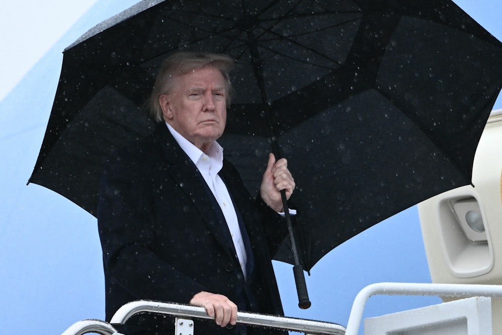 Trump holding umbrella in rain
