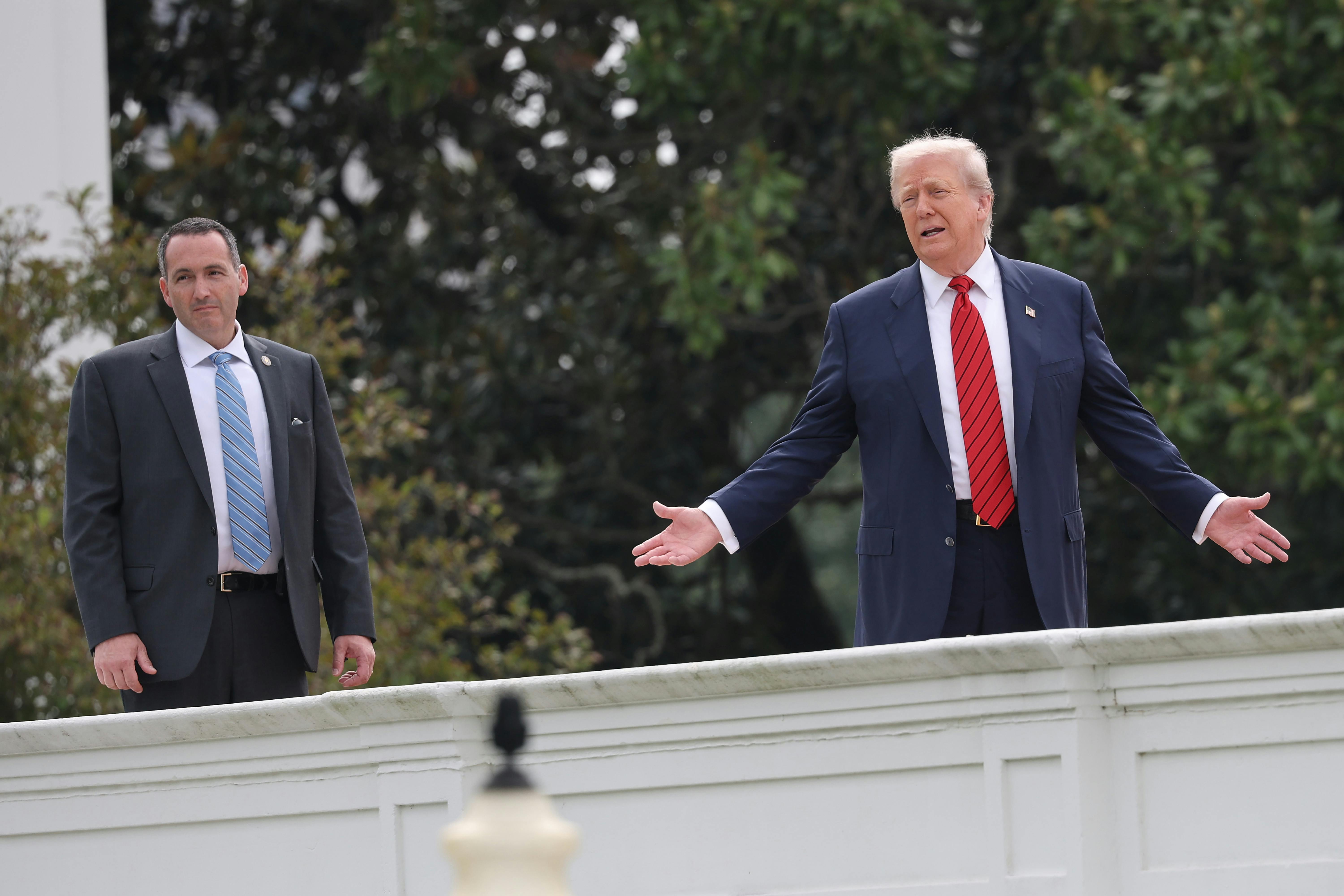 Donald Trump holds his arms out to the side while standing on the White House roof to oversee renovations
