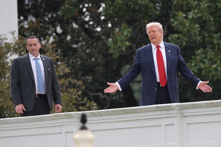 Donald Trump holds his arms out to the side while standing on the White House roof to oversee renovations
