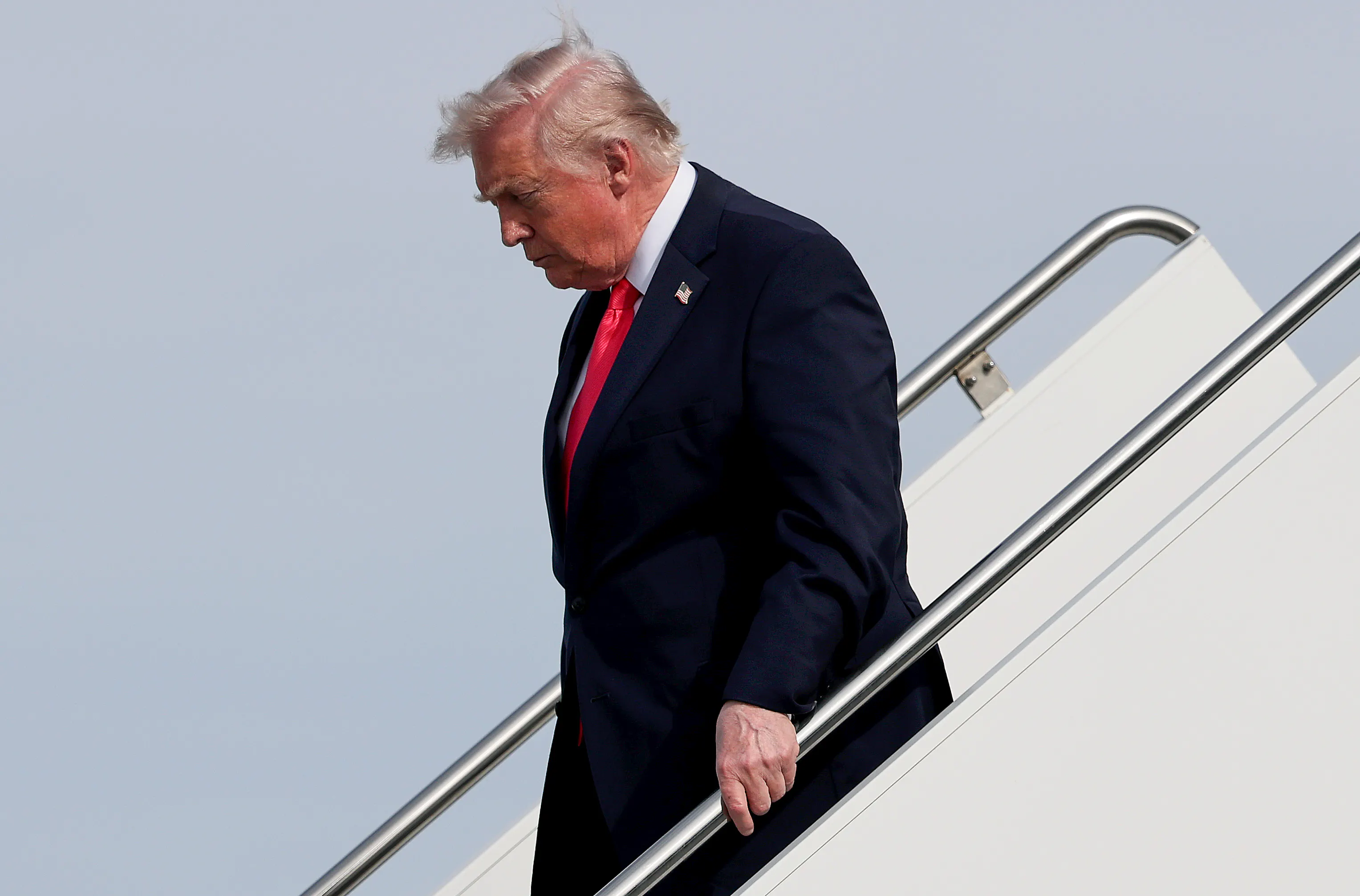 Donald Trump looks down while walking down the steps from Air Force One