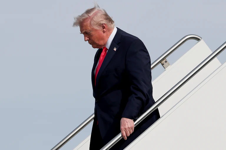 Donald Trump looks down while walking down the steps from Air Force One