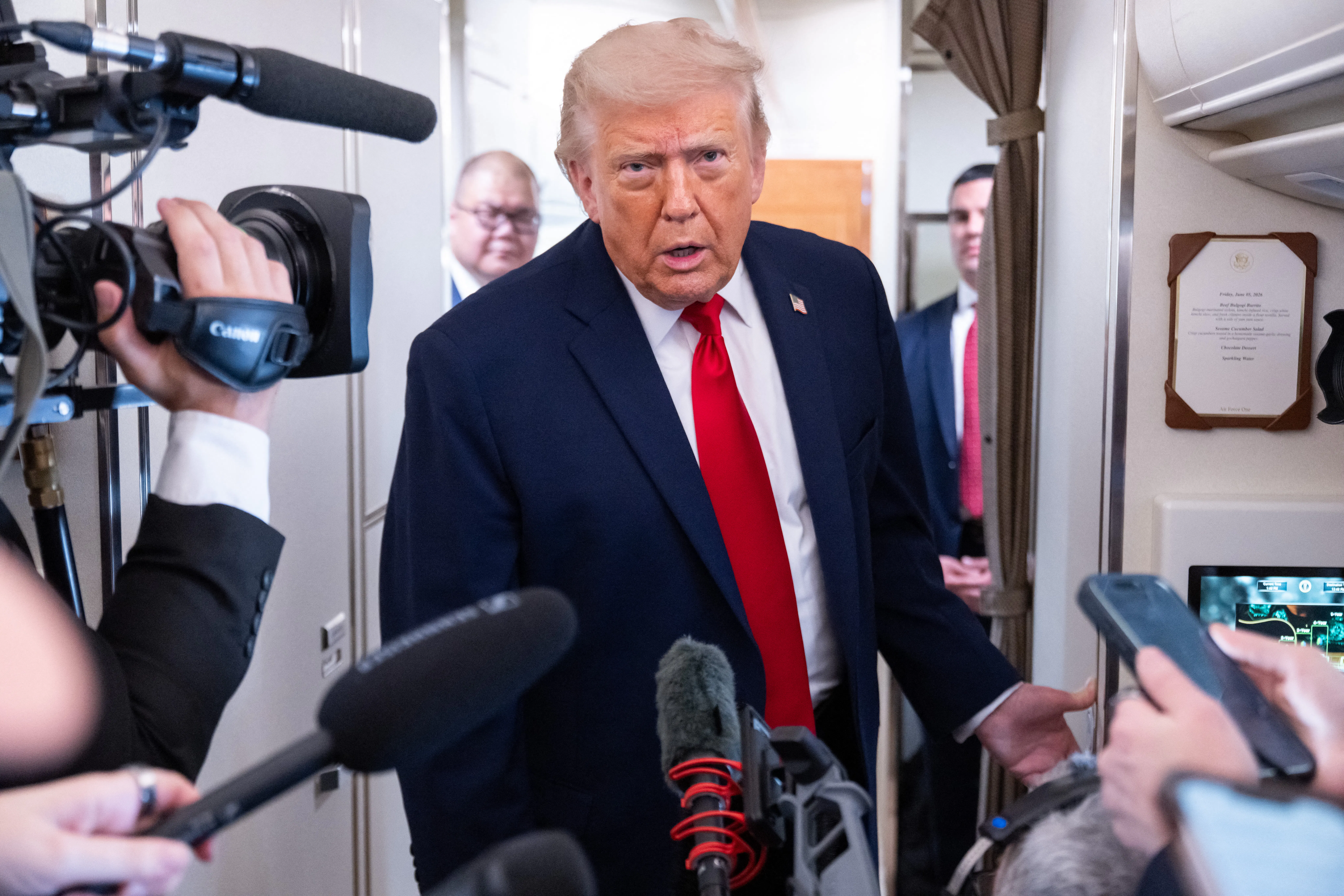 Donald Trump leans forward while speaking to reporters on Air Force One