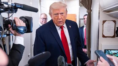 Donald Trump leans forward while speaking to reporters on Air Force One