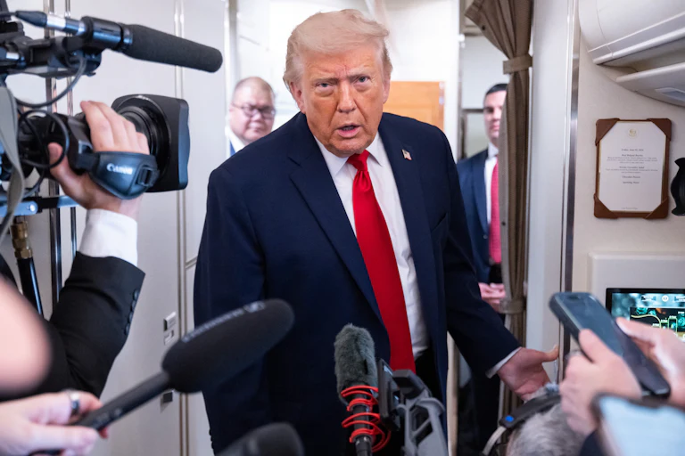 Donald Trump leans forward while speaking to reporters on Air Force One